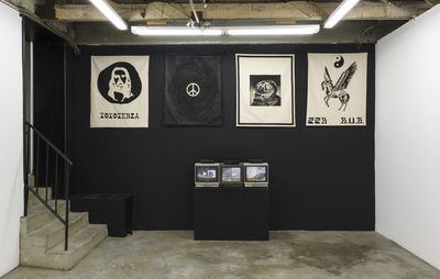 installation viwe of a black wall with various monochrome works of art hung up