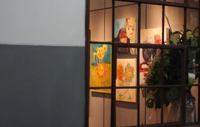 four works of art hung on a wall, viewed through a panelled window
