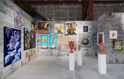 an installation view of various paintings hung on top of one another and three freestanding sculptures