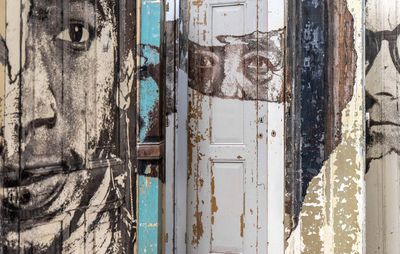 layers of wooden doors behind one another, each partly painted with a face on it
