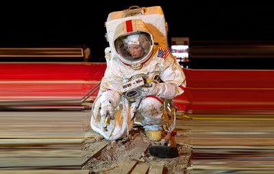 crouching astronaut on motion-blurred red and black background