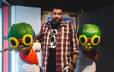 Hebru Brantley in between two sculptures of characters with green helmets and yellow goggles on