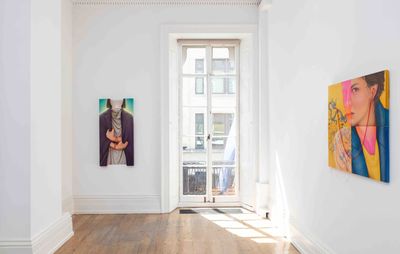 installation view of a white, light room, with two paintings hanging either side of a glass doorway