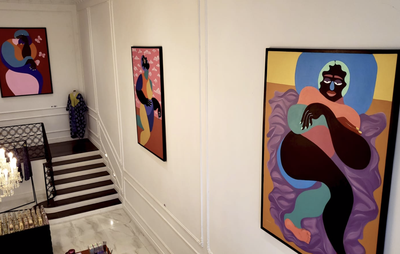 Three of Deborah Segun's paintings hanging on two white walls in an exhibition space above stairs
