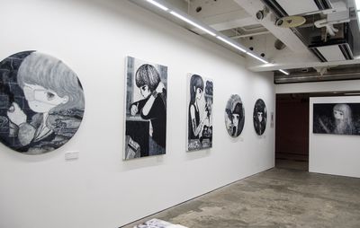 a line of monochromatic paintings hung on a white wall in varying tondo or rectangular shapes