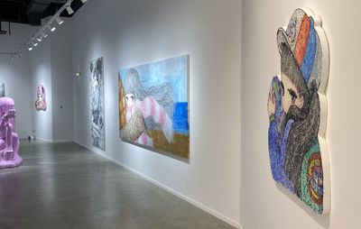 installation view of a pink sculpture in front of a wall of large paintings of female anime characters