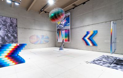 installation view of multicoloured pixelated sculptures and paintings hung in a large exhibition space