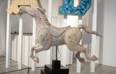 installation view of a horse sculpture with artwork behind it