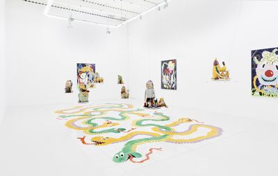 installation view of white exhibition space with large snake printed onto the floor, four sculptures spread across the room and six paintings hung on the walls