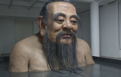installation view of giant sized elderly male, of his head and body from the chest upwards, jutting out of the floor 