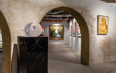 Artworks displayed on arches, behind a sculpture on a black plinth 