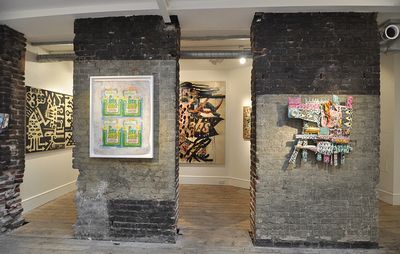 gallery space with crumbling, exposed walls and textural, collaged artworks