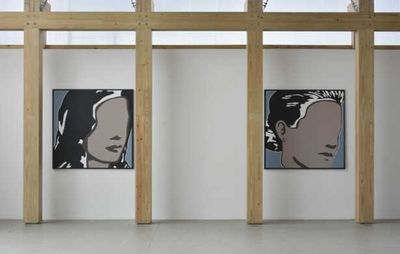 Installation view of wooden pillars with two portraits of faceless subjects between them