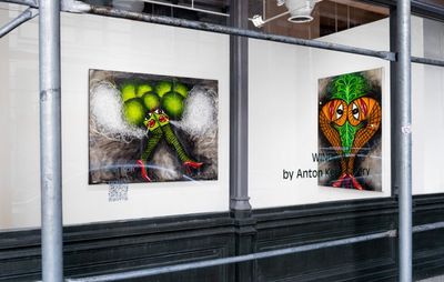 installation view of two paintings viewed through a glass window