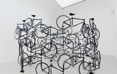 a sculpture by Ai Weiwei made up from dozens of black bicycles in a white room