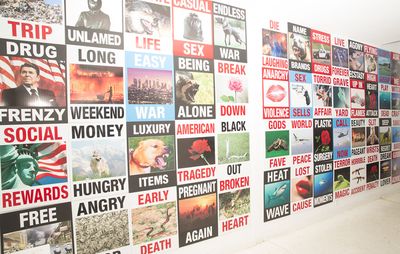 white wall filled with graphic posters with various images, colours and capitalised bodies of text on them