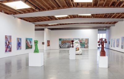 large open plan gallery space with several sculptural busts placed on plinths in the centre of the floor and a variety of colourful paintings surrounding them