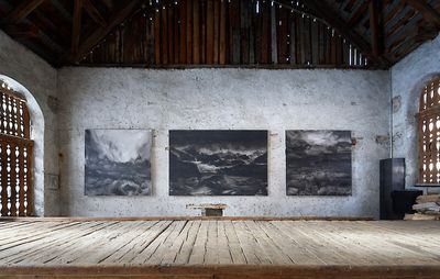 installation view of three paintings: two square paintings flanking a landscape painting