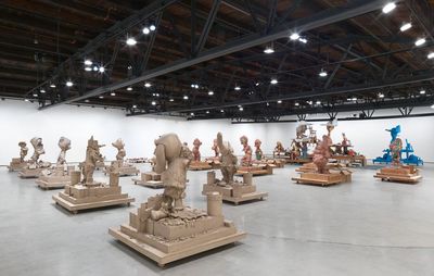 Sculptures lined up side by side in a large warehouse space