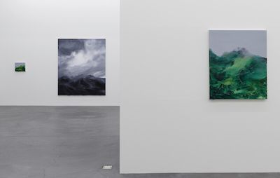 one white wall in front of another white wall, both with paintings of mountains and skies on them