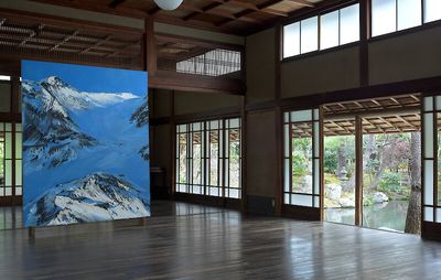 Installation view of open plan space with large scale painting of blue skies and snowy landscape scene