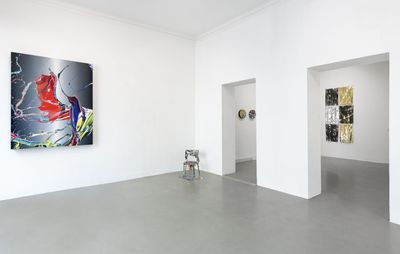 installation view of large painting of splashed colours hung on a wall with artwork in the background behind two doorways
