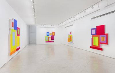 installation view of four neon geometric paintings hung on white walls