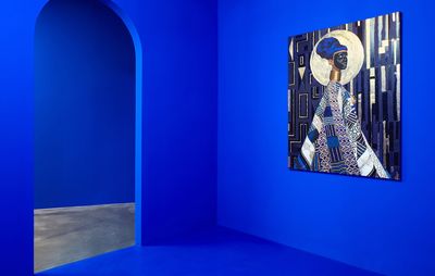 bold cobalt blue gallery wall with doorway on left hand side and blue, black and gold painting to its right