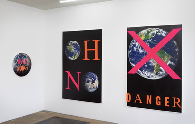 installation view of two rectangular and one round artwork hung on the wall, all containing images of planet Earth