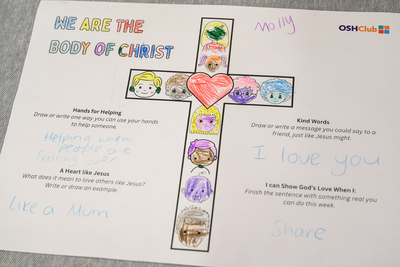 A child’s worksheet featuring a colorful cross with illustrated faces, surrounded by handwritten messages promoting kindness and love.