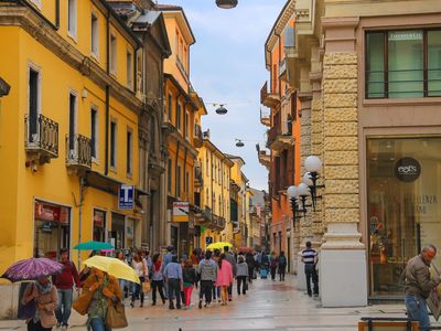 People walking around Verona with colourful umbrellas