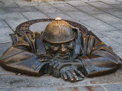 The Čumil, a bronze statue on a sewer worker resting on top of a manhole