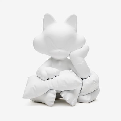 3D cat sculpture rendered in white pent leans upon two pilllows