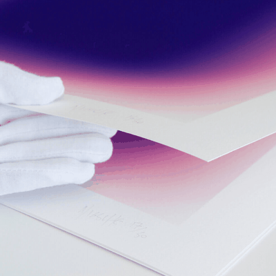 A hand in a white glove lifting up a pile of prints