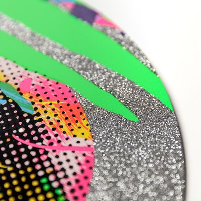 close-up of a round edge of a print with silver glitter and two green stripes