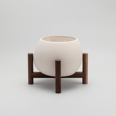 reverse view of a ceramic plant pot resting on a walnut wood stand
