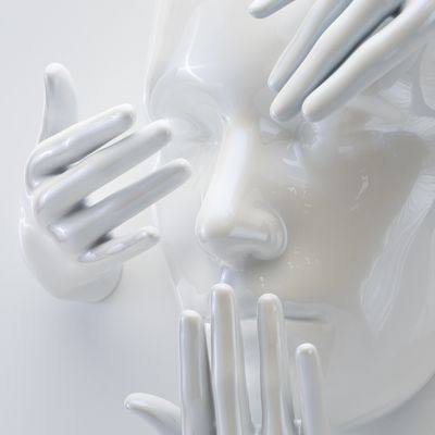 a close-up of a white gloss sculpture of a face emerging from a circular backboard