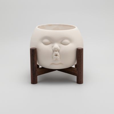 baby-faced ceramic plant pot on a walnut wood stand