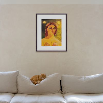 a print edition of a female portrait hung in a dark walnut frame above a linen sofa with a cat