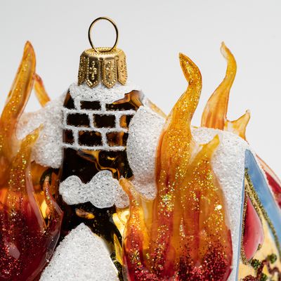 Top section of a glass ornament shaped like a burning gingerbread house