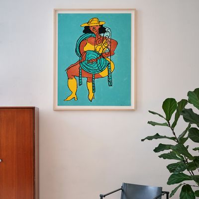 framed print by Tschabalala Self hung on a wall between a fiddle lead fig plant and a teak cupboard