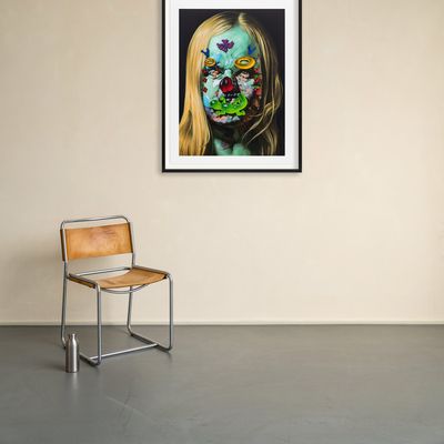 framed print hanging next to a leather and steel chair on an off-white wall