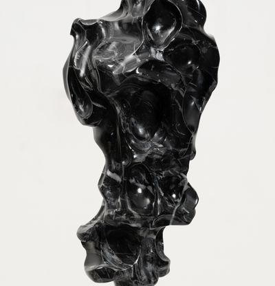 black marble sculpture resembling a face on a bronze pole by Kevin Francis Gray - side close up view