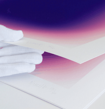 A hand in a white glove lifting up a pile of prints