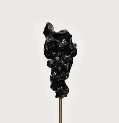 black marble sculpture resembling a face on a bronze pole by Kevin Francis Gray