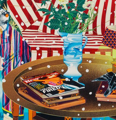 Detail of a table with magazines and a vase with flowers on, with a striped sofa in the background