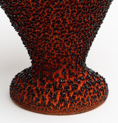 a curvaceous amphora painted in a red base coat with black textured flecks