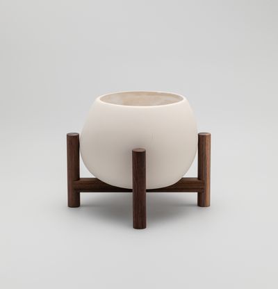 reverse view of a ceramic plant pot resting on a walnut wood stand
