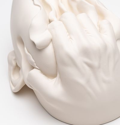 Hand rips through top of face sculpture