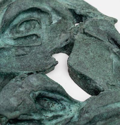 sculptural mask of a woman in green patina